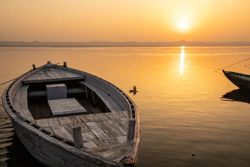 Wooden rowing boat on the still River Ganga at sunrise in Varanasi